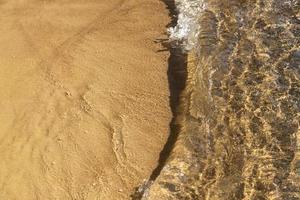 ola rompiendo en la orilla del mar de arena, vista desde la parte superior. antecedentes. foto