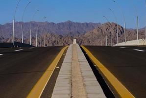 Asphalt roadbed stretching into the distance with mountains and sky, Sinai, Egypt. photo