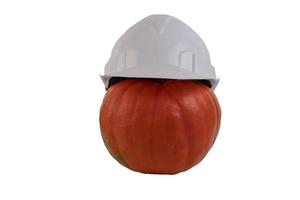 Orange pumpkin in a white construction helmet, helmet, on a white isolated background. photo