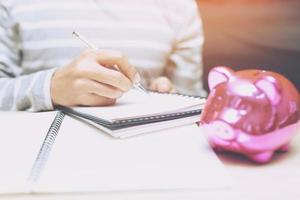 close up business woman hand holding in pen open the page notepad Office desk table with book, equipment supplies in the work spectacles and coffee cup. Top view with copy space on the page paper. photo