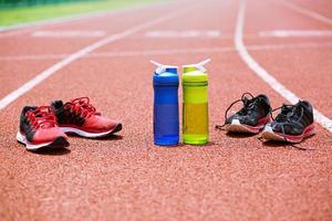 zapatos y botellas de agua beben en la pista de atletismo. concepto de ejercicio foto