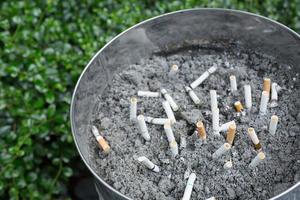 butt on cigarettes in the ashtray. There are many types of cigarette stub on the sand in the ashtray. A cigarette is not good for health. photo