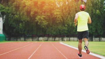 Young man running during sunny morning on stadium track photo