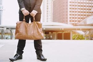 Closeup of a young businessman entrepreneur with boots and a briefcase stand office front photo