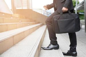 Close up legs of businessman walking stepping up stair person going up the stairs. Step forward confidently in a new start. grow up business concept. photo