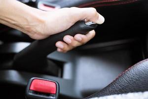 Closeup of person pulling hand brake lever in car For safety while parking. concept lock or unlock to protect against safety transport travel. photo