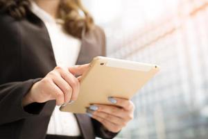 cerrar la mano de una mujer de negocios que trabaja con un dispositivo digital de tablet pc mientras está de pie frente a un edificio de oficinas con vistas a la ciudad.