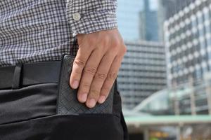 hombre confiado posando en caja fuerte manteniendo su billetera en el bolsillo trasero de sus pantalones de bolsillo trasero. ahorro dinero finanzas. foto