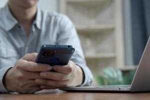 manos del hombre que usan el teléfono móvil y la computadora en el escritorio de la oficina. negocios que trabajan comunicaciones en línea comercio electrónico servicios de Internet en el concepto de oficina en casa. foto