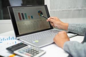 Asian accountant working and analyzing financial reports project accounting with chart graph in modern office, finance and business concept. photo