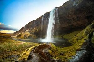 seljalandsfoss, una cascada con una pequeña cueva detrás en la región sur de islandia, es parte del río seljalands que tiene su origen en el volcán glaciar eyjafjallajokull foto