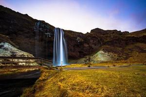 Seljalandsfoss, a waterfall with a small cave behind it in the south region in Iceland, it is part of the Seljalands River that has its origin in the volcano glacier Eyjafjallajokull photo