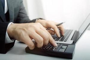 Woman entrepreneur using a calculator with a pen in her hand, calculating financial expense at home office photo