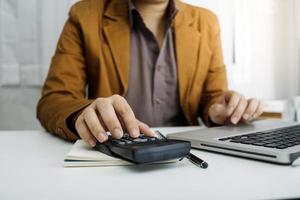 Woman entrepreneur using a calculator with a pen in her hand, calculating financial expense at home office photo