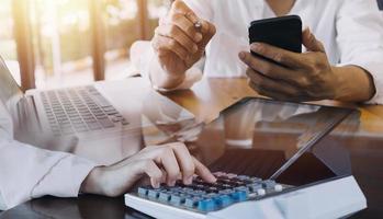 compañeros de trabajo de la sociedad comercial que usan una tableta para analizar el informe del presupuesto financiero de la empresa y el progreso del trabajo de costos y la planificación para el futuro en la sala de la oficina. foto