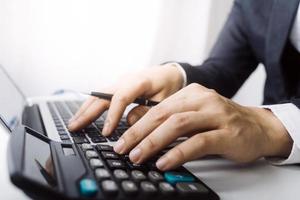 Woman entrepreneur using a calculator with a pen in her hand, calculating financial expense at home office photo