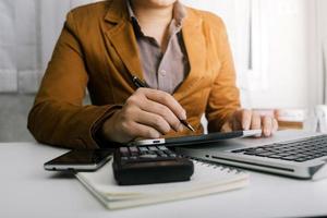 Woman entrepreneur using a calculator with a pen in her hand, calculating financial expense at home office photo