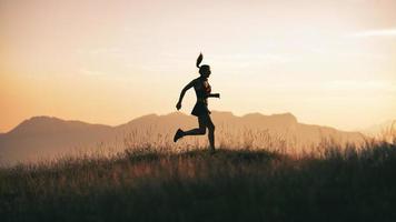 una joven deportista corre al atardecer en las colinas foto