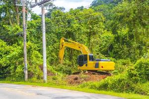 grandes excavaciones de excavadoras amarillas destruyen la jungla forestal en phuket, tailandia. foto