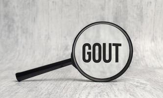 On the magnifier is the text GOUT on white background photo