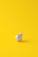 Christmas yellow minimal background with grey ball. Close up, copy space photo