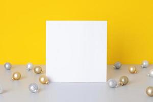 Christmas yellow and grey minimal background with mock up greetings card and ball. Close up, copy space photo