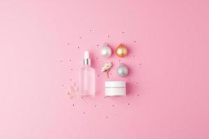 Exhibición de productos cosméticos navideños. productos para el cuidado de la piel sobre fondo rosa. endecha plana, espacio de copia foto