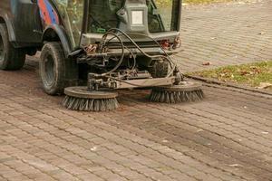 The municipal service conducts seasonal work in the park. The sweeper picks up a lot of debris. The brushes sweep the asphalt photo