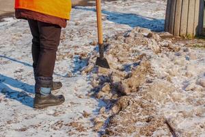 una trabajadora limpia el hielo y quita la nieve de las losas de pavimentación con un rompehielos. foto