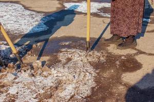 una trabajadora limpia el hielo y quita la nieve de las losas de pavimentación con un rompehielos. foto