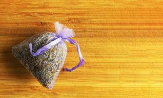 Lavender sachet for home and wardrobe freshener, natural anti-repellant, transparent organza bag with fragrant dried flowers, on a wooden background photo