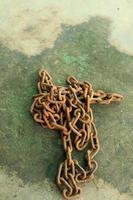 Rusty and dirty steel chains on cement floor in front of the house for locking valuable assets such as motorcycles and bicycles to prevent guerrilla theft. photo