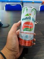 Jakarta, Indonesia in July 2021. A hand holds a can of fizzy drink with the Nutriville brand. NutriVille Collagen Drink with Lychee Flavo photo