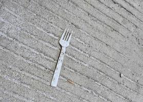 A plastic fork litter on top of a concrete road. Ab photo