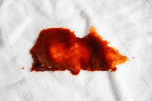 Dirty tomato sauce stain or ketchup on cloth to wash with washing powder, cleaning housework concept. photo