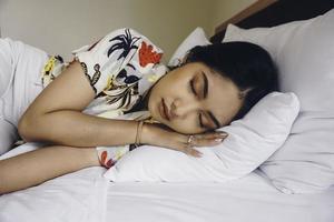 mujer joven y atractiva durmiendo en el dormitorio, está acostada a un lado y relajándose con los ojos cerrados foto