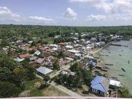 Aerial view of village near beautiful beach with small island in the background in Maluku, Indonesia photo