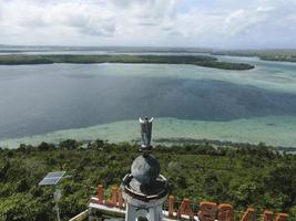 Aerial view of Jesus statue with beautiful beach view in small island. Maluku, Indonesia - July, 2022 photo