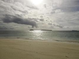 Beautiful sunny day on a calm pristine beach with grey skies in Indonesia photo