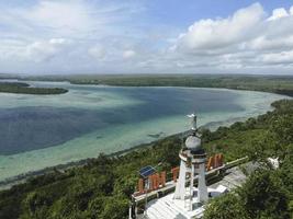 vista aérea de la estatua de jesús con hermosa vista a la playa en una pequeña isla. maluku, indonesia - julio, 2022 foto