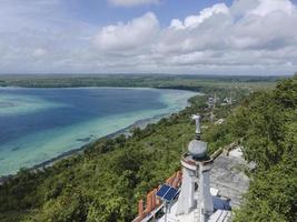 Aerial view of Jesus statue with beautiful beach view in small island. Maluku, Indonesia - July, 2022 photo