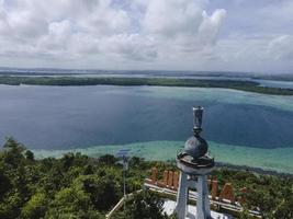 vista aérea de la estatua de jesús con hermosa vista a la playa en una pequeña isla. maluku, indonesia - julio, 2022