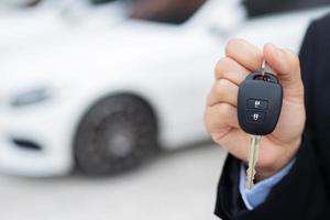 Salesman is carrying the car keys delivered to the customer at the showroom with a low interest offer. Special promotion photo