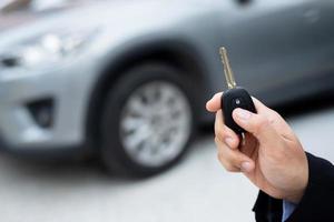 Salesman is carrying the car keys delivered to the customer at the showroom with a low interest offer. Special promotion photo