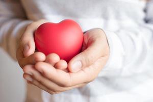 joven doctora sosteniendo un corazón rojo sobre un fondo blanco foto