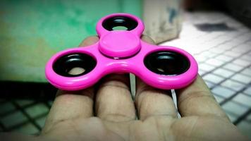 young man playing with a fidget spinner, focus on spinner photo