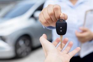 el vendedor lleva las llaves del auto entregadas al cliente en la sala de exposición con una oferta de bajo interés. promoción especial foto