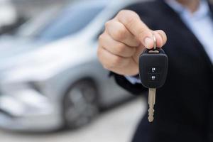 Salesman is carrying the car keys delivered to the customer at the showroom with a low interest offer. Special promotion photo