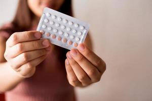 Women holding birth control pills, focus hand photo