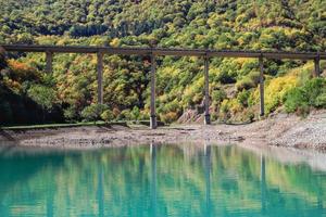 Scenic view on the lake with blue water and bridge on background of mountains in autumn season. Caucasus Mountains, Georgia. photo